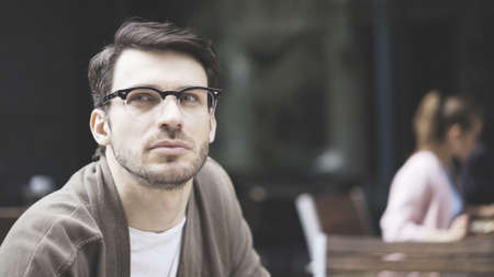 A closeup of handsome man dressed in a gray jacket and white shirt wearing eyeglasses outdoorsの写真素材