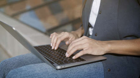 Female hands typing on a keyboard in a small laptop outdoors in the summerの写真素材