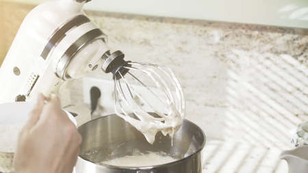 Closeup of perfectly whipped white cream on a mixer. Beaten eggs white and whipped cream in a mixer bowlの写真素材