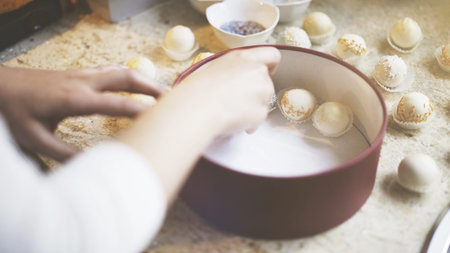 The woman puts white chocolate sweets into a rounded box. Handmade sweets accurately lying in a red...