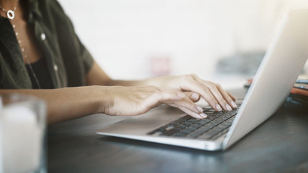 Close up of white woman elegant hands on black keyboard of a laptop at home
