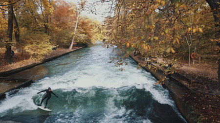 MUNICH, GERMANY, November 18, 2019: Real time shot of Urban Surfers on a wave on the Eisbach river....