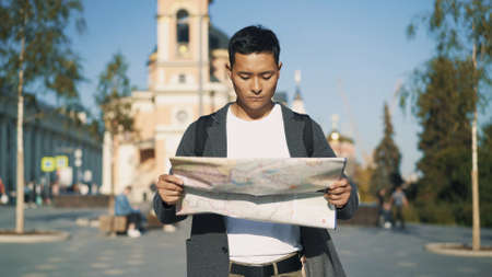 Front portrait shot of a young Asian man looking at a map. Tourist in Moscow. Travel concept.の写真素材