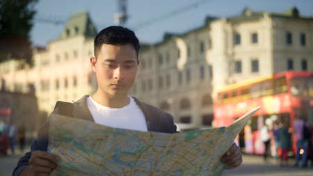 Side view portrait shot of a young Asian man looking at a map. Tourist in Moscow. Travel concept.の写真素材