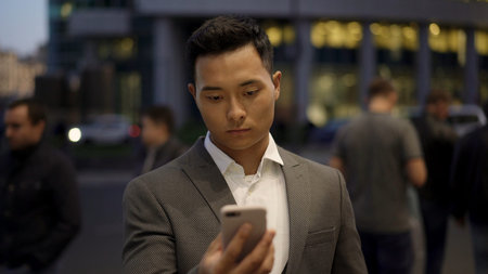 Front view of a young asian businessman, leading correspondence on the phone. Financial business area. Night time at business city.の写真素材