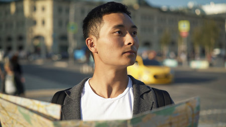 Side view portrait shot of a young Asian man looking at a map. Tourist in Moscow. Travel concept.の写真素材