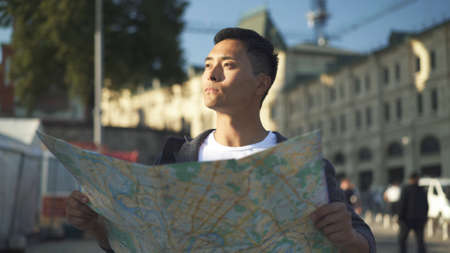 Side view portrait shot of a young Asian man looking at a map. Tourist in Moscow. Travel concept.の写真素材