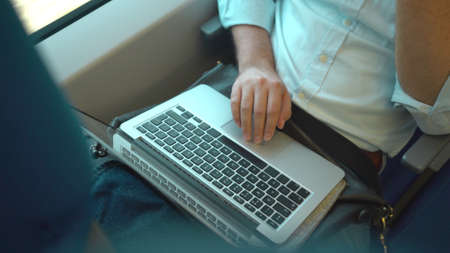 Top view of an unrecognizable businessman s hands using his laptop while he is riding a trainの写真素材