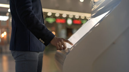Young businessman hands dressed in jacket swiping for information in kiosk on background of lights...