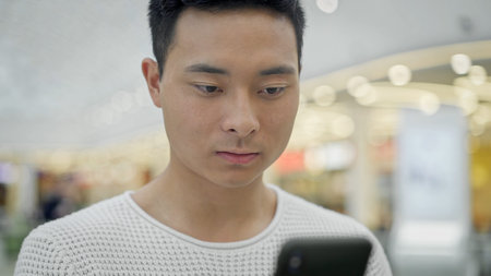 Portrait close up shot of smiling black hair asian male wearing white sweatshirt standing and...