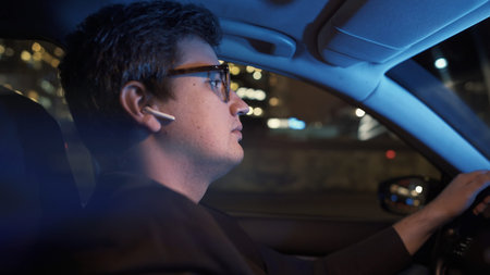Man driving the car in earbuds, profile gimbal shot. Close up profile portrait shot of man in...
