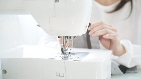 Concept of sewing courses in modern bright studio, sewing in process, blurred background. Female...