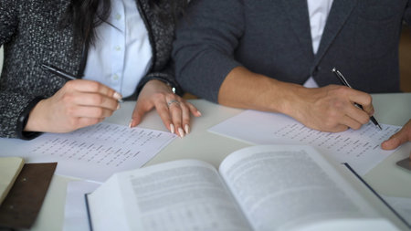 Male and female studying for the exam, top view shot of hands and papers with task. Male and female...