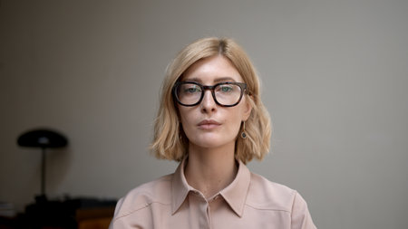 Portrait of blonde woman in eyeglasses smiling. Attractive stylish adult person looking at the camera with sincere and happy smile. Concept of good mood.の写真素材
