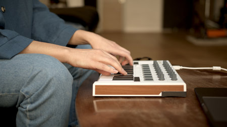 Woman hands playing on small keyboard, producer of music. Closeup of hands playing on keys, home recording studio with professional equipment.の写真素材