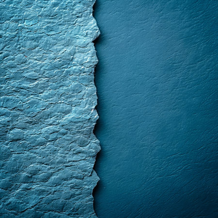 A piece of textured blue paper displays a torn edge, revealing a smooth, darker blue surface underneath. The contrast highlights the beauty of paper art and design materials..の素材
