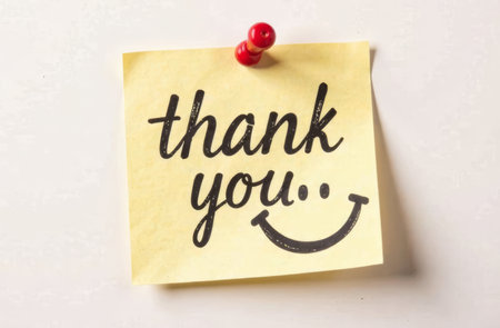A bright yellow sticky note displays the message thank you accompanied by a cheerful smiley face. It is pinned to a clean, light-colored surface, conveying appreciation and positivity..の素材