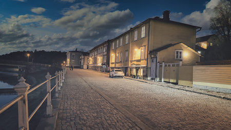 Porvoo, Finland - December 08, 2020: Cobblestone street scene at night, featuring illuminated buildings and a serene atmosphere, reflecting calmness and urban charmの写真素材