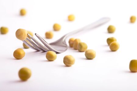 fork with one pea pinned and others scattered aroundの写真素材