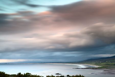 dark clouds during sunset over Irish coast Dingle peninsula Kerry district hills and beach long exposure image give a dramatic lookの写真素材