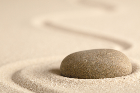 Zen meditation stone with raked line in sand. Concept for harmony relaxation and purity.の写真素材