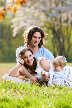 Young family together in grass on the meadowの写真素材