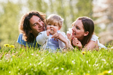 Young family together in grass on the meadowの写真素材
