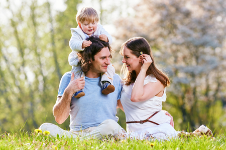 Young family together in grass on the meadowの写真素材