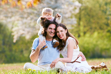 Young family together in grass on the meadowの写真素材