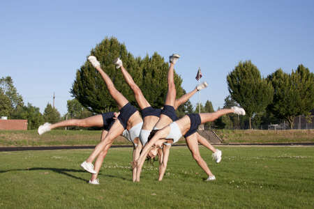 A composite of a female athlete performing a cartwheel on a grassy field.の写真素材