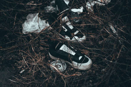 Black shoes left on the autumn ground near a roadの写真素材