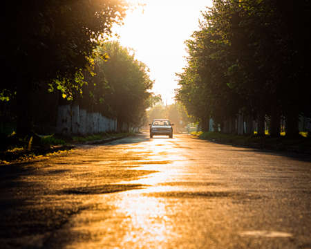 Road with lonely car. Red sunset light and high contrast.の写真素材
