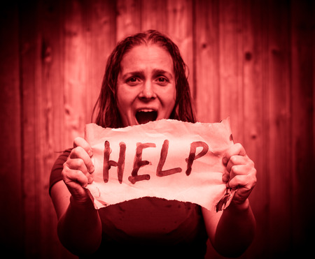A girl holding a sheet of paper on which is written "help".の写真素材