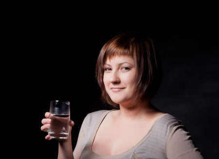 young woman with glass water, black backgroundの写真素材
