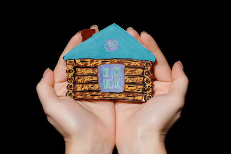 painted house in hands on black backgroundの写真素材