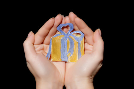 painted a gift in hands on black backgroundの写真素材