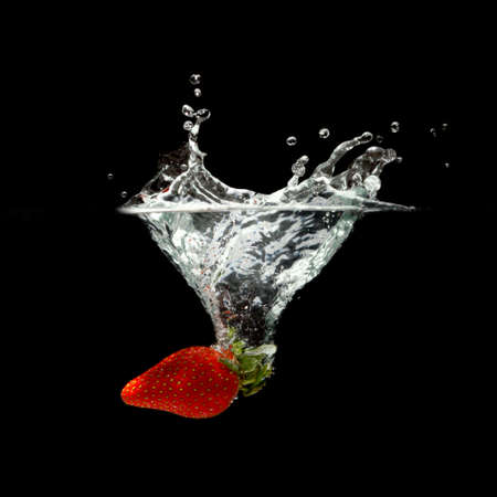strawberry splashing in water over black backgroundの写真素材