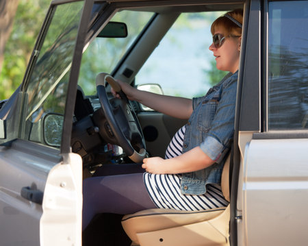 Pregnant woman at the wheel of big carの写真素材