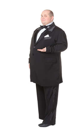 Elegant very fat man in a dinner jacket and bow tie winking mischievously and pointing with his finger across his belly , three quarter studio portrait on whiteの写真素材