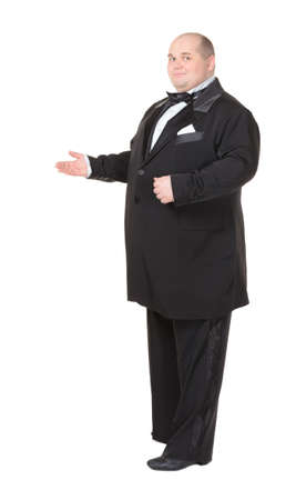 Elegant fat man in a dinner jacket and bow tie smiling charmingly as he holds out his hand to the side gesturing in that directionの写真素材