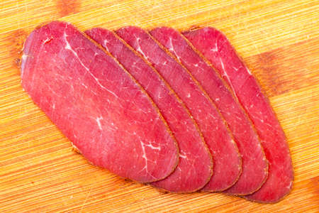 Slices of Smoked Meat, on wood backgroundの写真素材