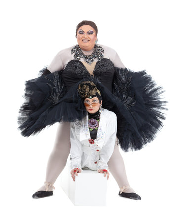 Two drag queens performing together in humorous caricature of women, on white