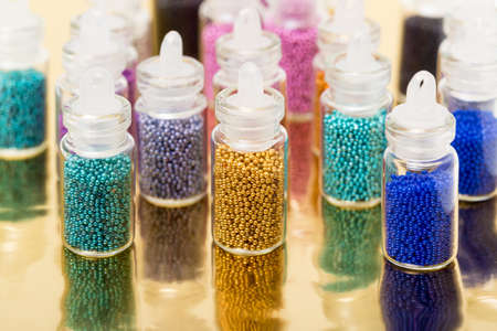 Small Glass Jars filled with Balls of Bead, on golden backgroundの写真素材