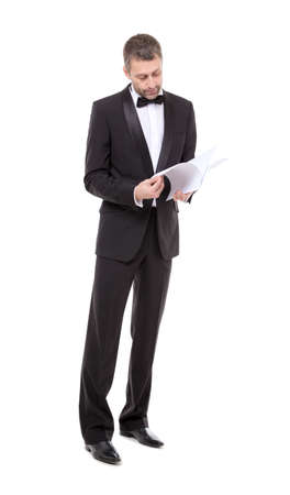 Stylish middle-aged man in a bow tie and tuxedo reading the document in his handの写真素材