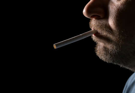 Portrait man smoking cigarette, closeup on black backgroundの写真素材
