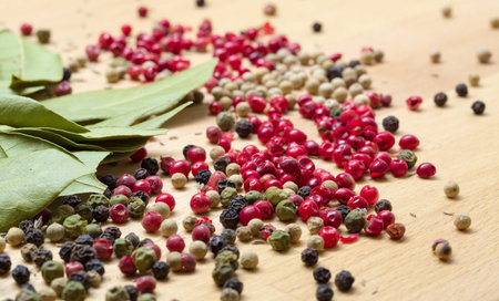 Dry bay laurel leaf with multicolored peppercorn closeup on wooden background