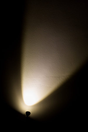 Dark Wall Illuminated from the Left Corner Spotlight Lamp, black backgroundの写真素材