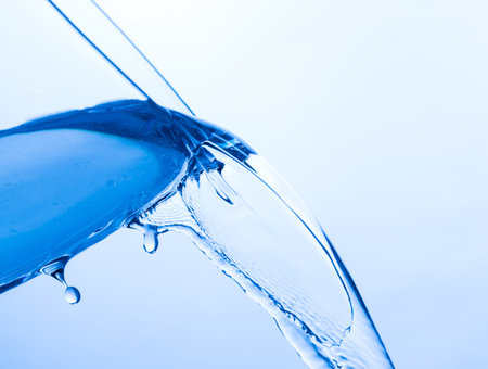 Cool Water Pouring from a Transparent Glass Cup, close upの写真素材