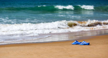 Women's Blue Slippers on a Sandy Ocean Beach, summer vacation conceptの写真素材
