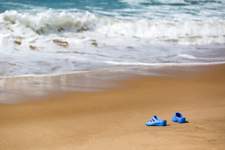 Women's Blue Slippers on a Sandy Ocean Beach, summer vacation conceptの写真素材